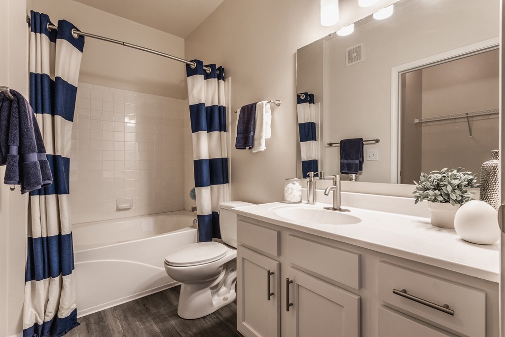 a bathroom with a white sink and toilet next to a white bathtub with a shower curtain