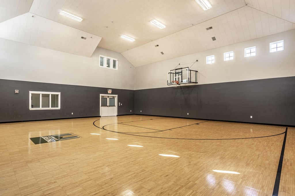 a large gym with a basketball hoop and wood floors