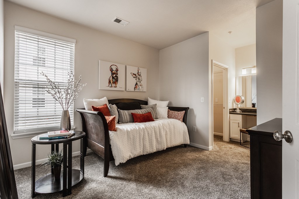 a bedroom with a bed and a chair in front of a window