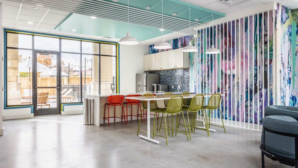 A kitchen in a lounge three red barstools, next to a table surrounded by six green chairs.