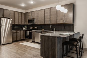 A modern kitchen with dark wood cabinets and stainless steel appliances.