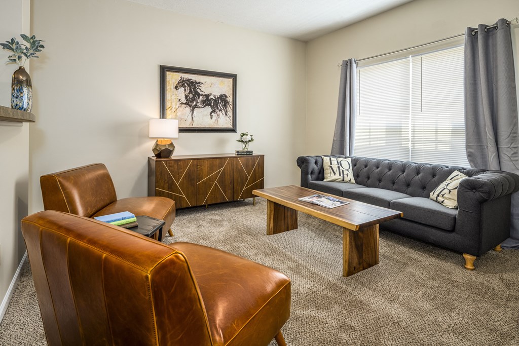 Pickerington, OH Apartments - Arbors at Turnberry - Furnished Living Room with Carpet Flooring, Window, Sofa, Leather Chairs, Coffee Table, and Side Table