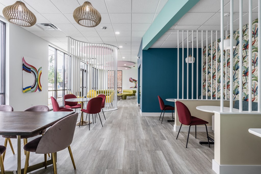 Co-working lounges at Madamore Apartments with tables and chairs, stylish decor, and windows.