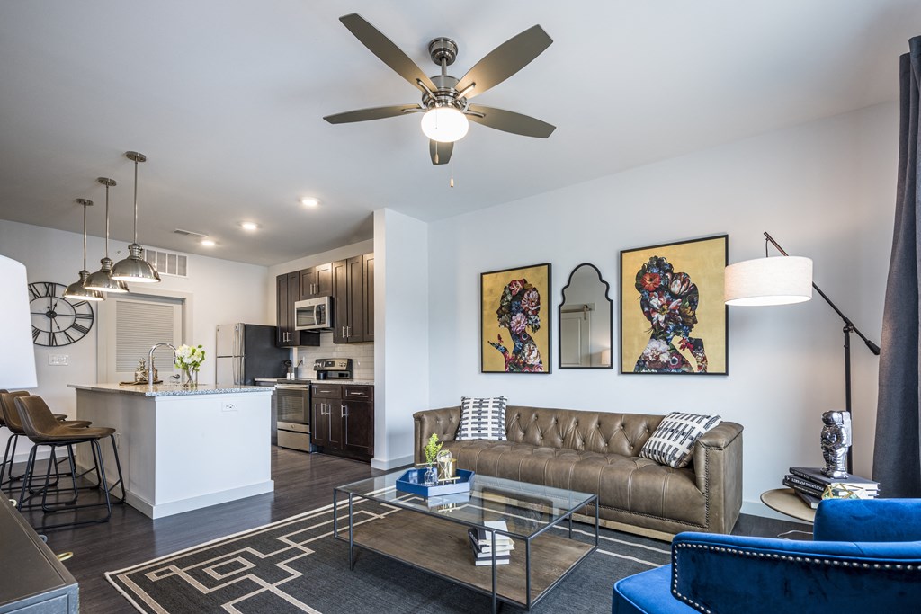 A furnished living room with a rig, next to a kitchen on hardwood-style floors in Cincinnati, OH.