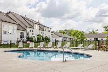 A swimming pool surrounded by lounge chairs and apartment buildings.