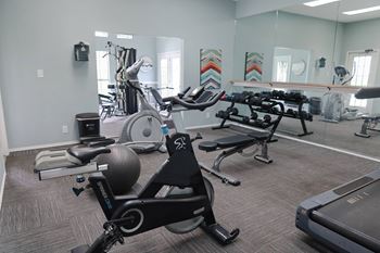 A gym with a variety of equipment including treadmills, weights, and exercise machines.