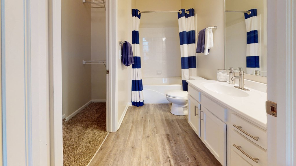 a bathroom with white cabinets and a blue and white striped shower curtain