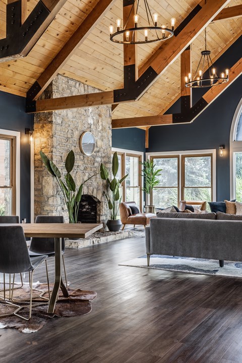 A modern living room with a stone fireplace and wooden beams.