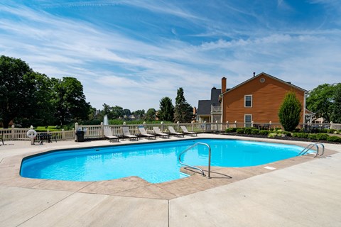 A large outdoor swimming pool with a slide and a house in the background.