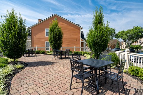 A wooden house with a patio and chairs.