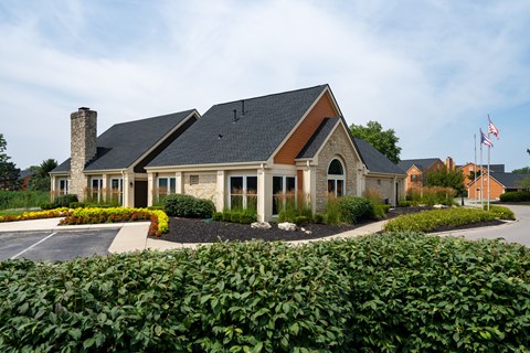 A house with a flag on the roof and a driveway in front.