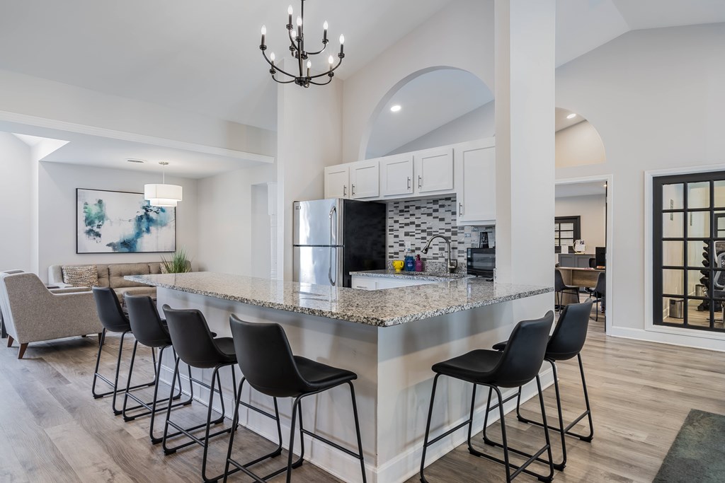 A kitchen with a marble countertop and black barstools.