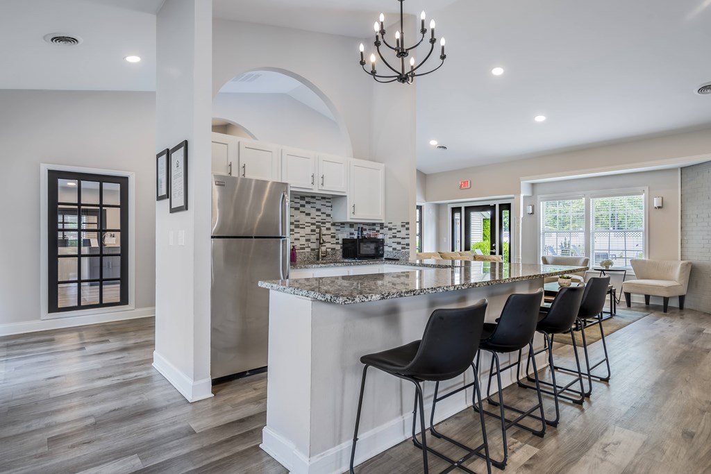 A kitchen with a bar and chairs.