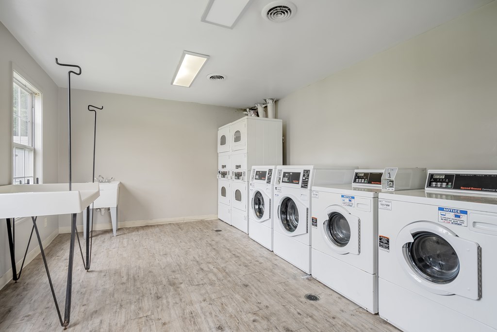 A laundry room with a white table and a row of washing machines.
