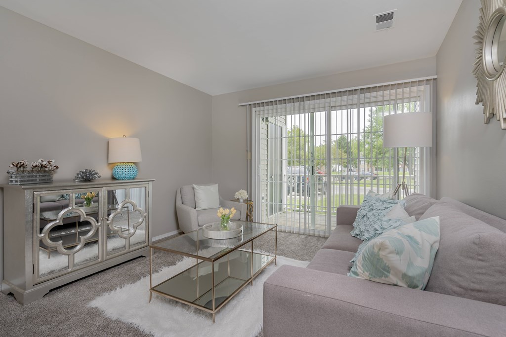 A living room with a grey couch, a glass coffee table, and a silver cabinet.