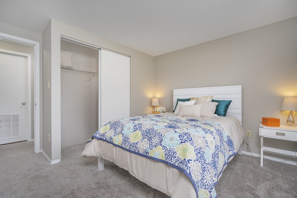 A bedroom with a bed, nightstand, and lamp.