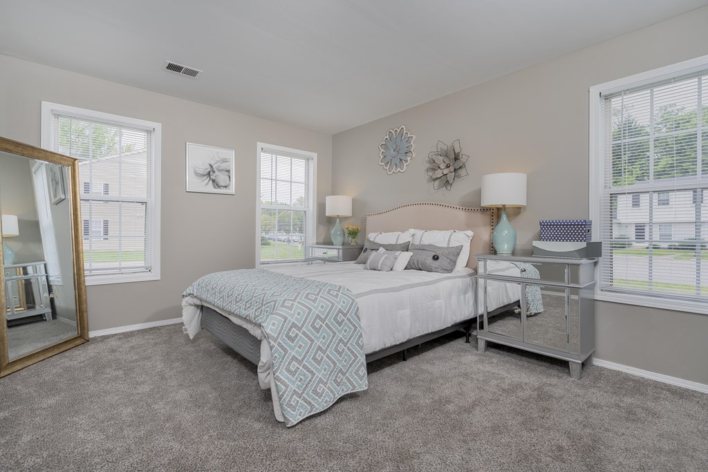 A bedroom with a large bed and a mirror on the wall.