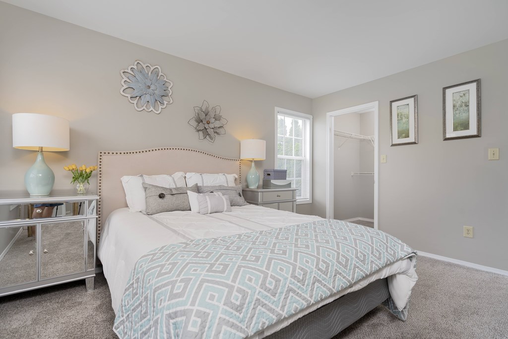 A bedroom with a large bed and a nightstand with a lamp.