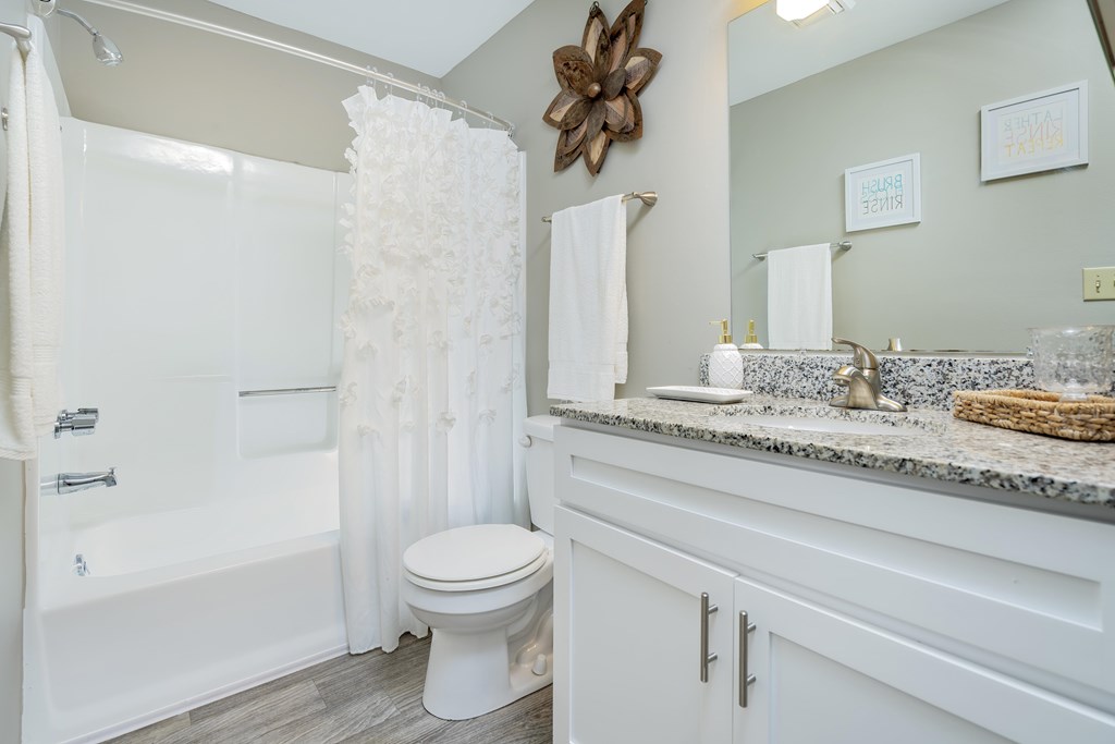 A white bathroom with a toilet, sink, and shower.