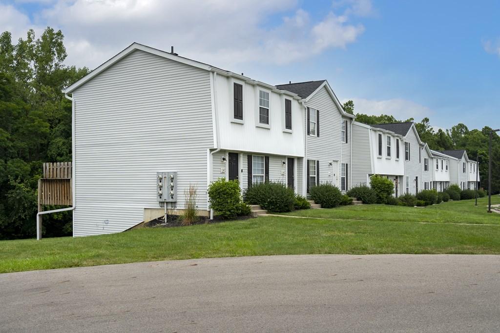 A white house with a grey roof and a grey lawn in front.