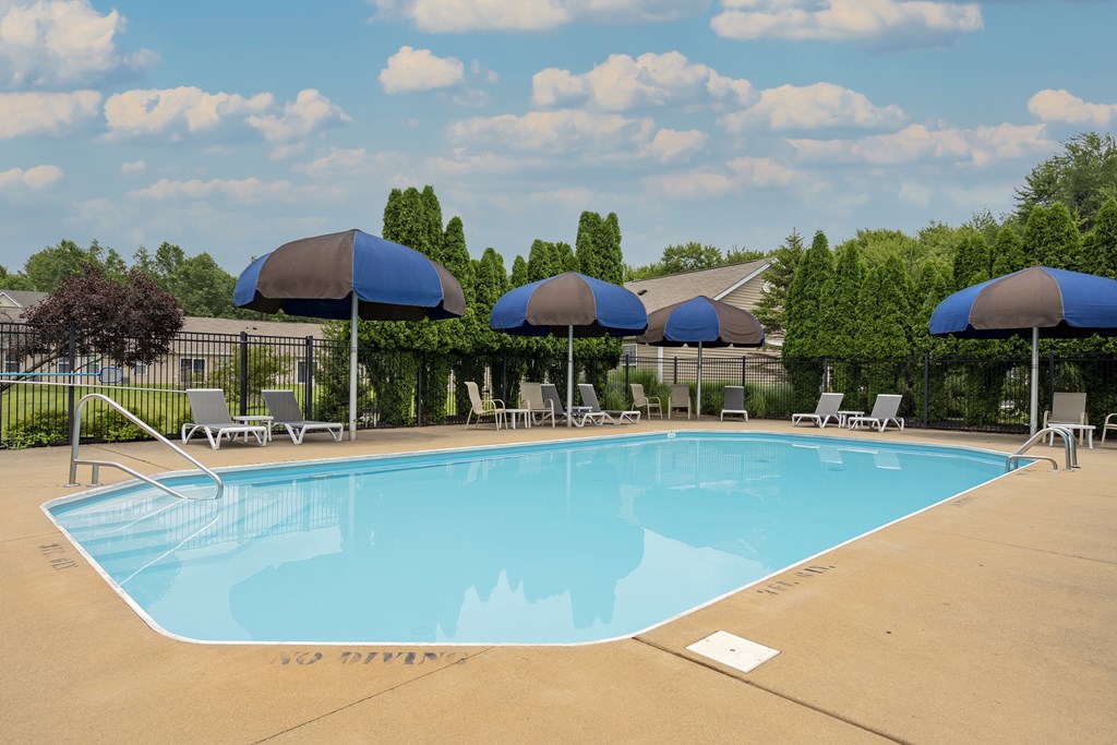 A large swimming pool with blue umbrellas and chairs.