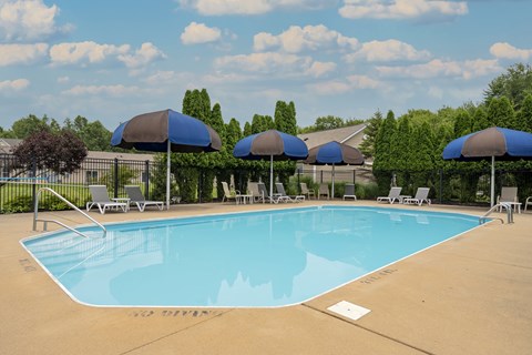 A large swimming pool with blue umbrellas and chairs.