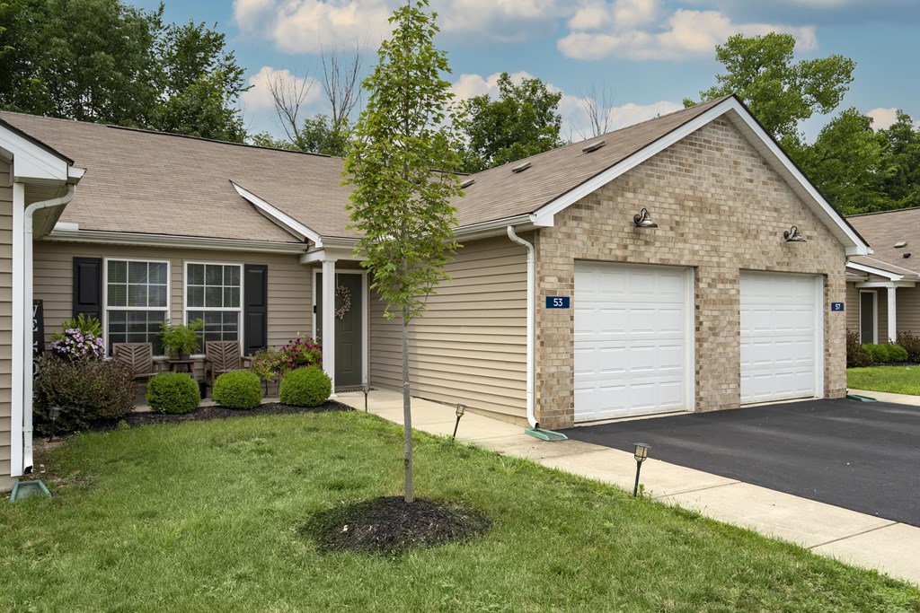 A house with a garage and a tree in front of it.