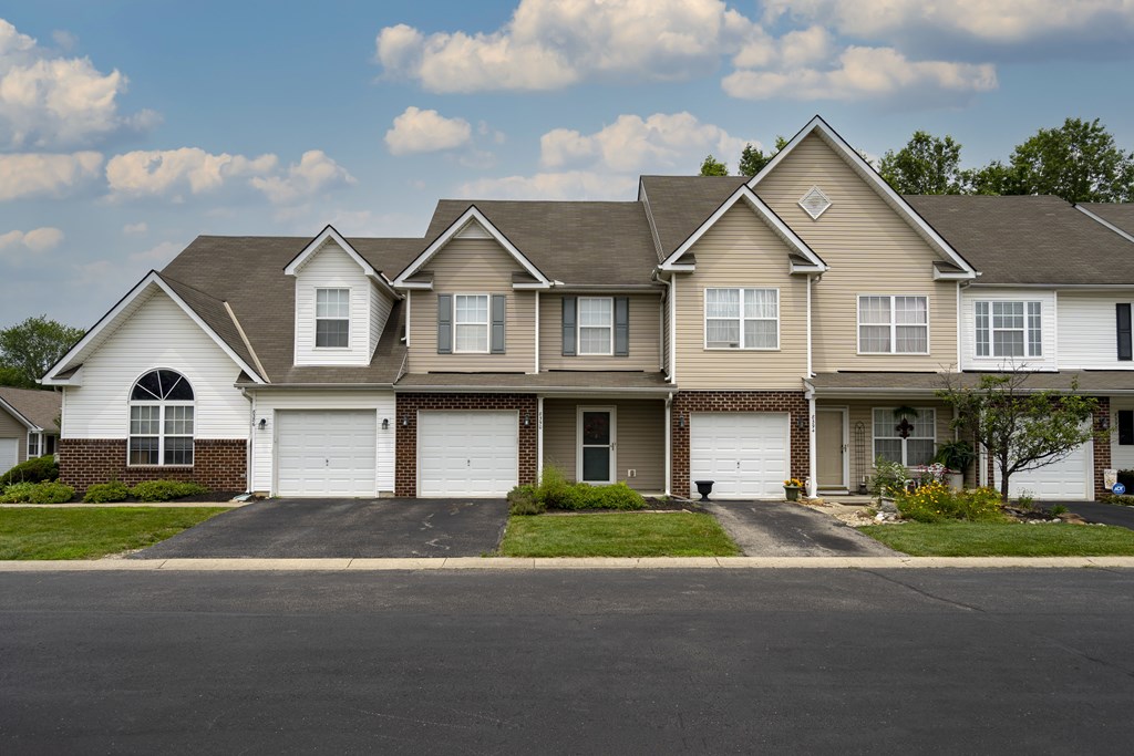 A large, two-story house with a garage is situated on a street.
