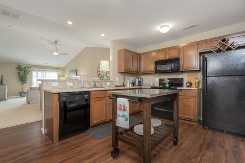 A kitchen with a black refrigerator and wooden cabinets.