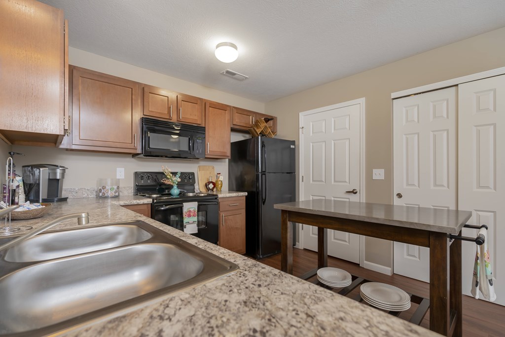 A kitchen with a refrigerator, microwave, oven, and sink.