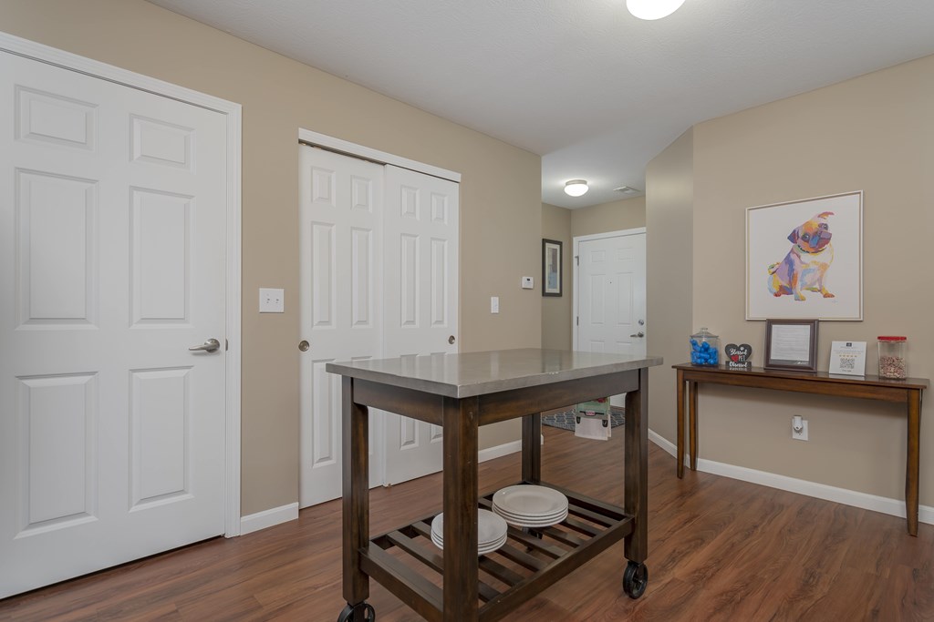 A kitchen island with a cart on wheels is in the middle of a room with two doors.