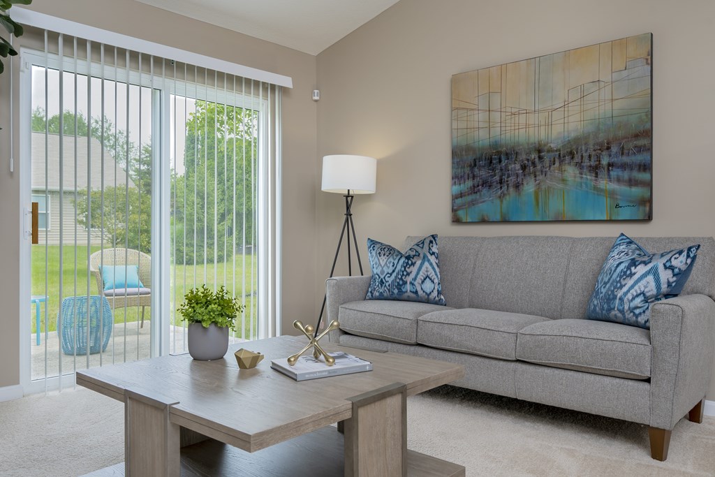 A living room with a grey couch, a wooden table, and a painting on the wall.