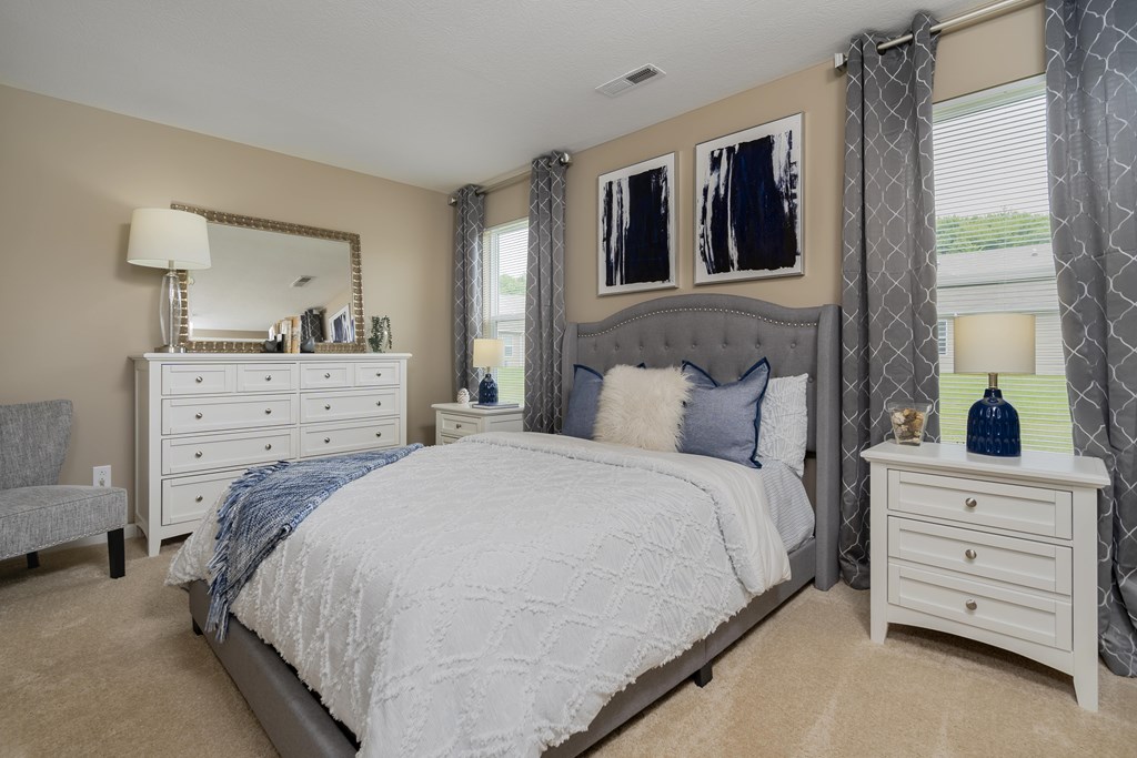 A bedroom with a large bed, a dresser, and a mirror.