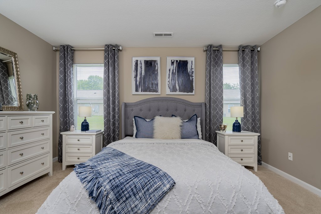 A bedroom with a large bed, two nightstands, and a dresser.