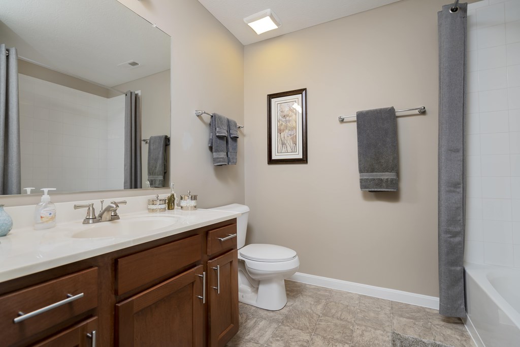 A bathroom with a toilet, sink, and mirror.