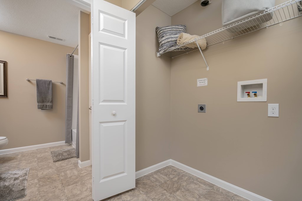 A white door is open to a bathroom with beige walls.