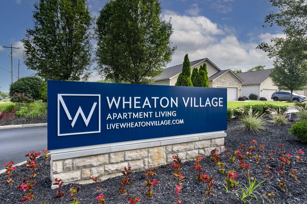 Wheaton Village Apartment Living sign in front of some houses.