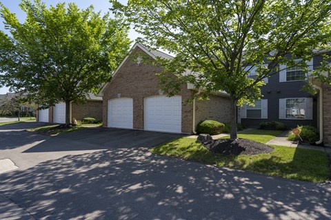 A house with a driveway and two trees in front.