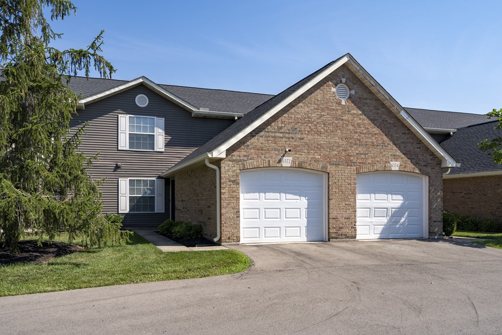 A house with a grey roof and two white garage doors.