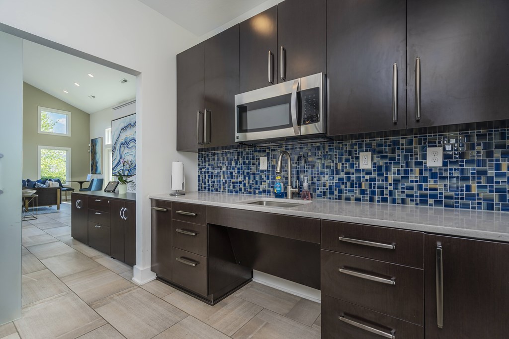 A kitchen with dark brown cabinets and a blue tile backsplash.