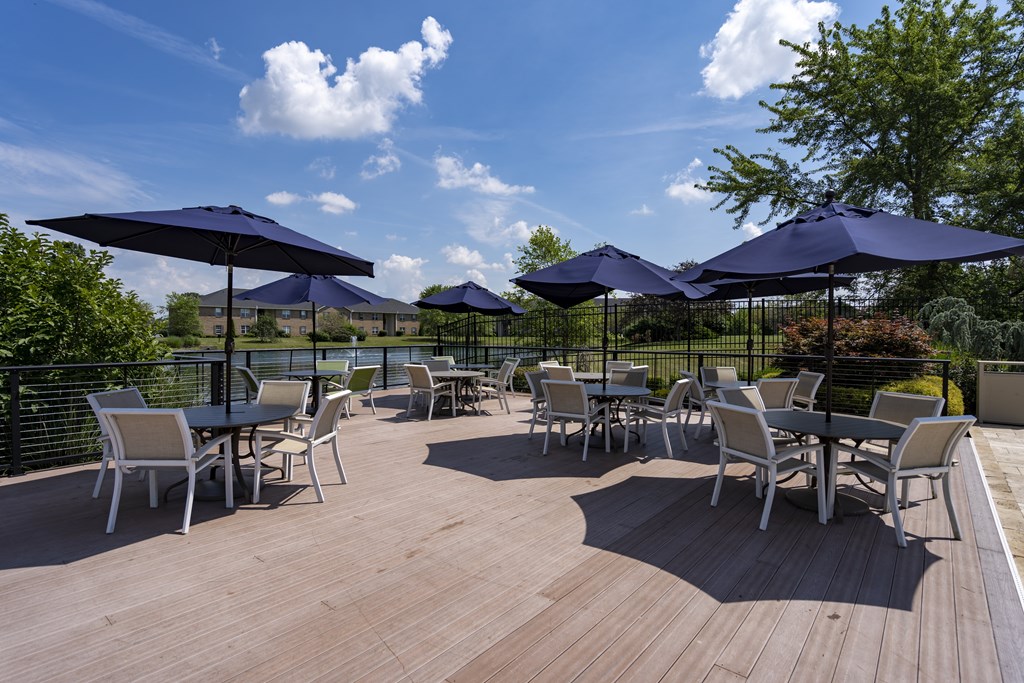 A wooden deck with chairs and umbrellas.