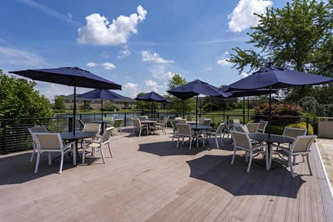 A wooden deck with chairs and umbrellas.