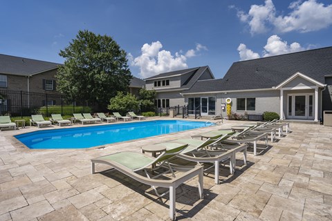 A pool surrounded by lounge chairs and a building in the background.