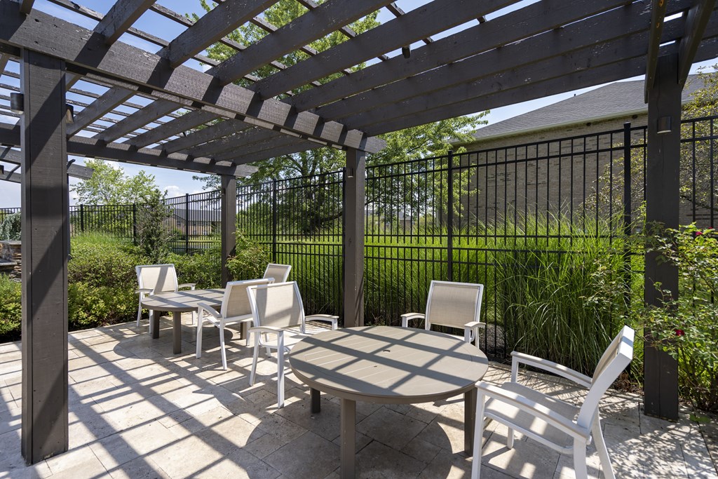 A patio with a table and chairs under a pergola.