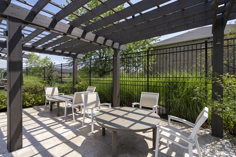 A patio with a table and chairs under a pergola.