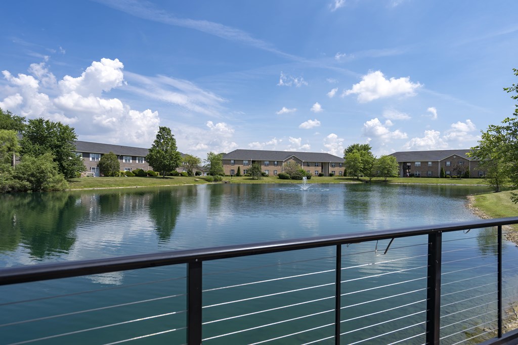 A serene lake surrounded by buildings and trees under a clear blue sky.