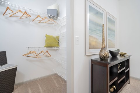 A room with a white wall and a wooden shelf with a vase on it.