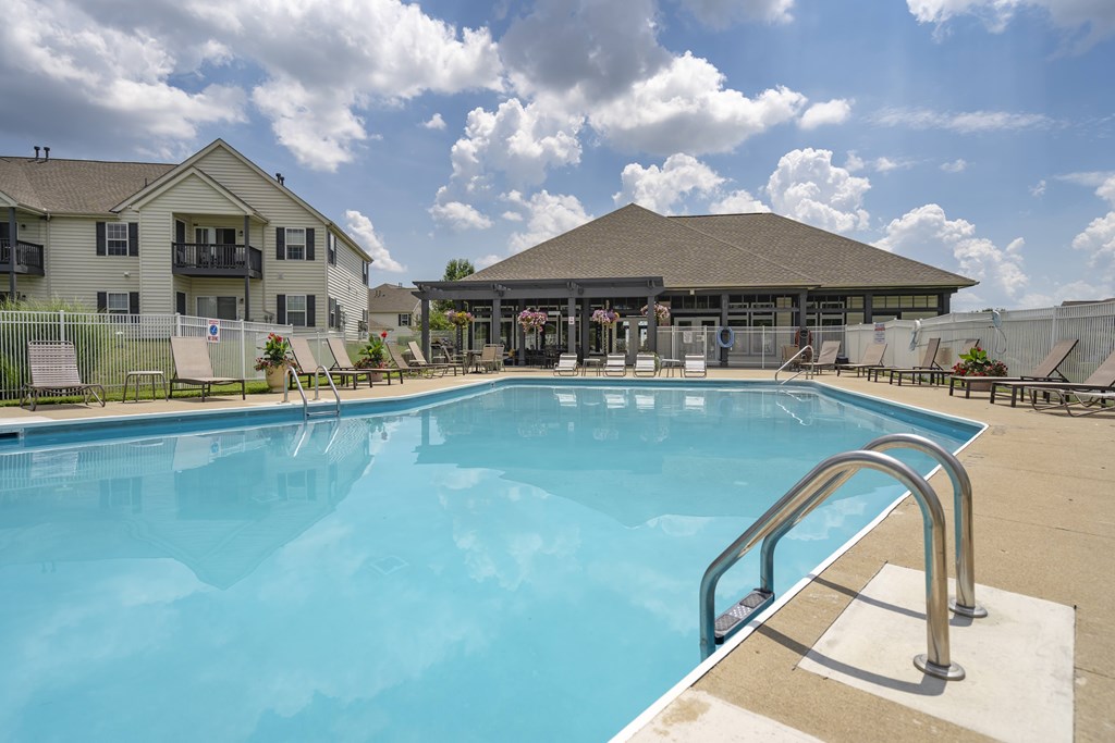 A large swimming pool with a metal ladder in the foreground and a building in the background.