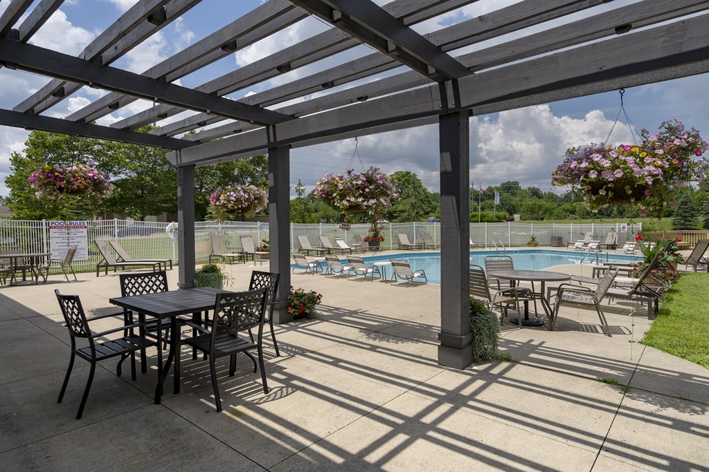 A patio with a table and chairs overlooking a pool.