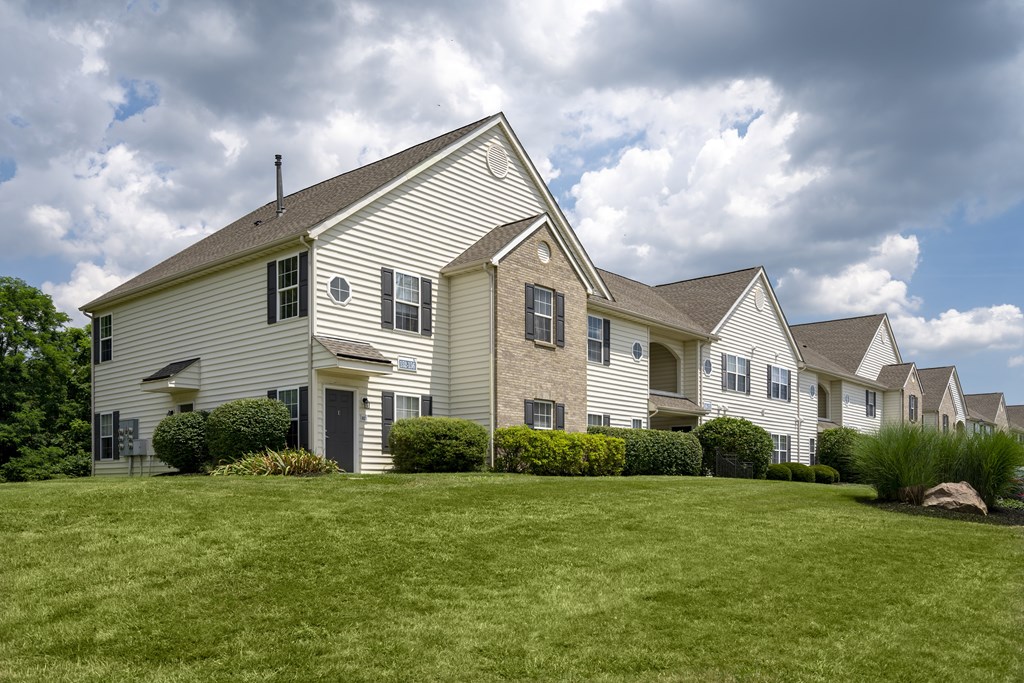 A large white house with a grey roof and a green lawn in front.